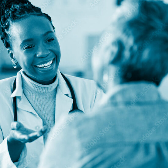 African American healthcare professional wearing a white lab coat and a stethoscope, smiling as she converses with an older patient